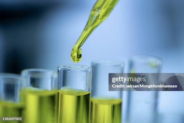 closeup of a female scientist in a laboratory working with cbd oil extracted from a marijuana plant. she is tearing the cbd oil from one tube into another - life sciences stock-fotos und bilder