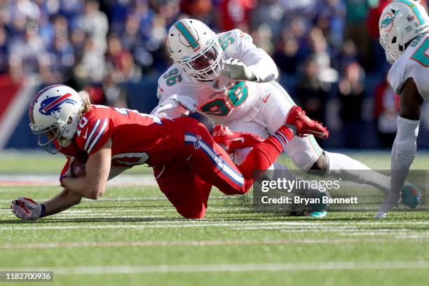 Cole Beasley of the Buffalo Bills falls to the ground as Taco Charlton of the Miami Dolphins tackles him during the third quarter of an NFL game at...