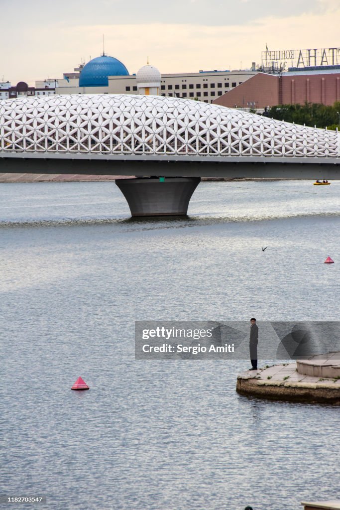 Man by Ishim river with Atyrau bridge