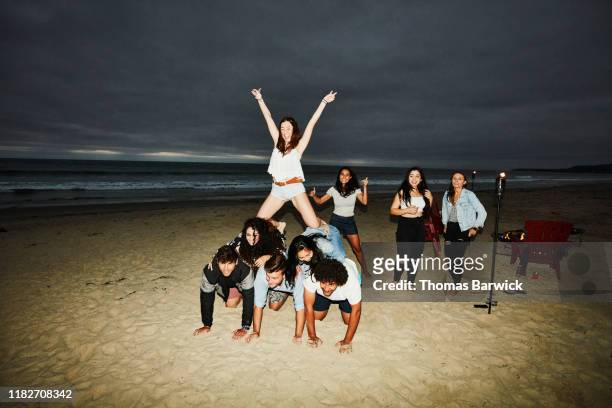 woman celebrating while making human pyramid with friends during beach party - human pyramid ストックフォトと画像