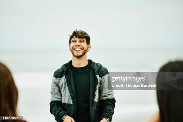 man laughing with friends during summer beach party - abrigo gris fotografías e imágenes de stock