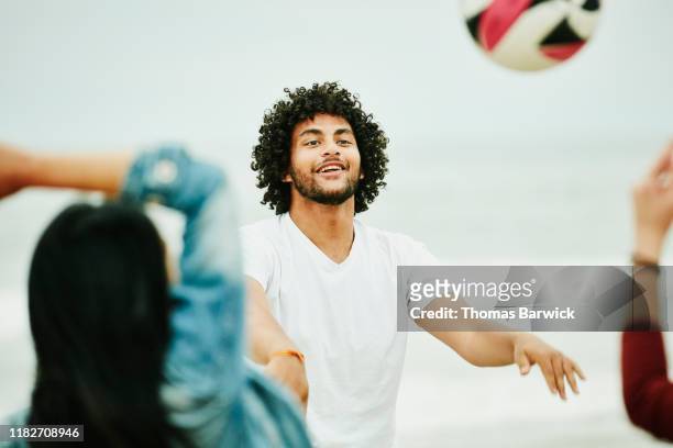 Man playing volleyball with friends during beach party