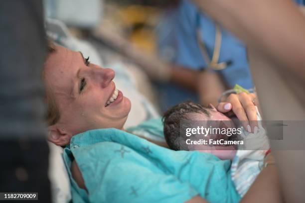 une mère retenant son bébé nouveau-né dans la salle d'accouchement pour la première fois la photo de stock - baby delivery photos et images de collection