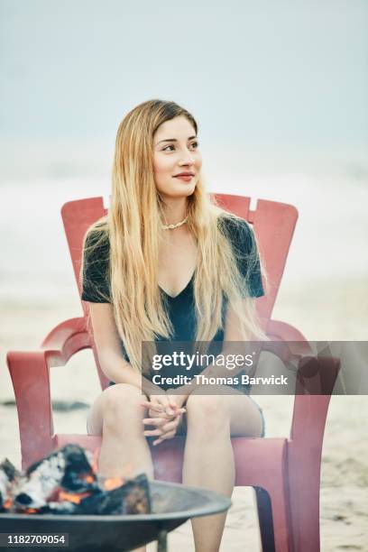 smiling woman sitting by fire in beach chair during party - red hot summer party stock pictures, royalty-free photos & images