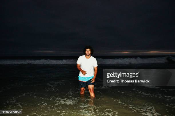 smiling man wading in surf on summer evening - coolpad stockfoto's en -beelden