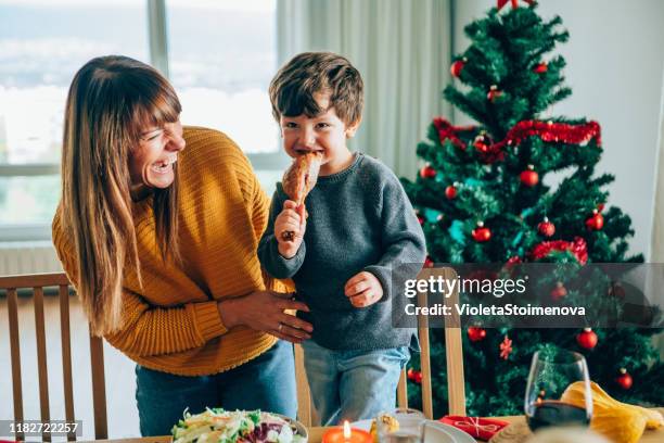 happy mother and her son having fun while biting turkey leg - turkey leg stock pictures, royalty-free photos & images