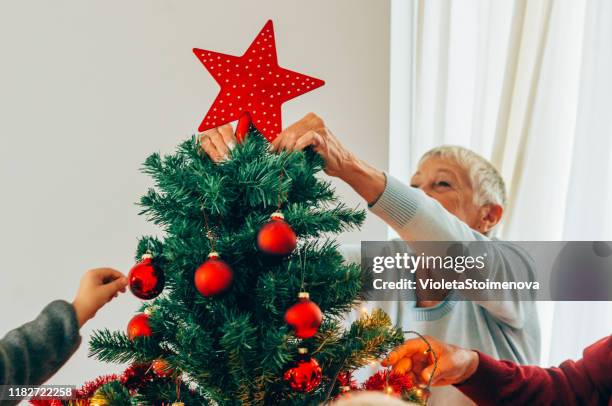 seniorin schmückt den weihnachtsbaum - dekoration für die weihnachtsbaumspitze stock-fotos und bilder