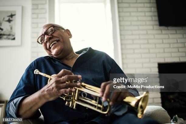 portrait of senior man with trumpet - freizeit stock-fotos und bilder