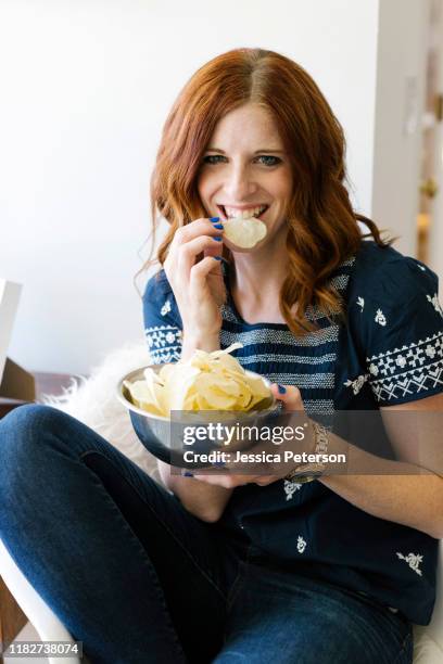 smiling woman eating crisps from bowl - one potato chip stock pictures, royalty-free photos & images