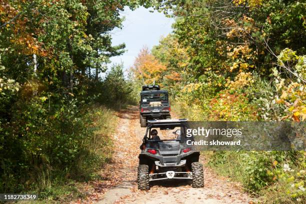 trail riding on 4x4 side-by-side off-road vehicles - side by side atv stock pictures, royalty-free photos & images