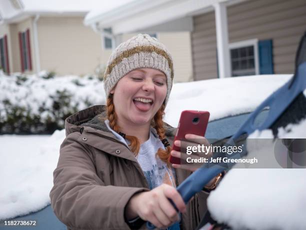 girl taking selfie while brushing snow off of car - blacksburg stock pictures, royalty-free photos & images