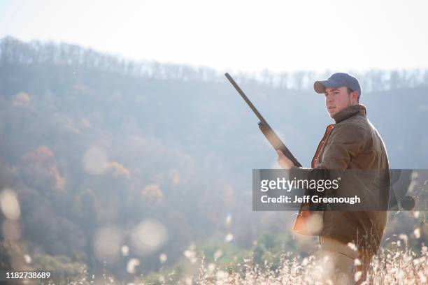 young man holding rifle in field - winchester virginia stock pictures, royalty-free photos & images