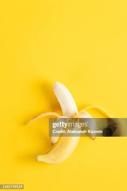 banana on yellow surface - geschält stock-fotos und bilder