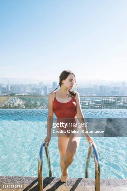 young woman wearing red swimsuit in rooftop swimming pool in kuala lumpur, malaysia - badeanzug stock-fotos und bilder