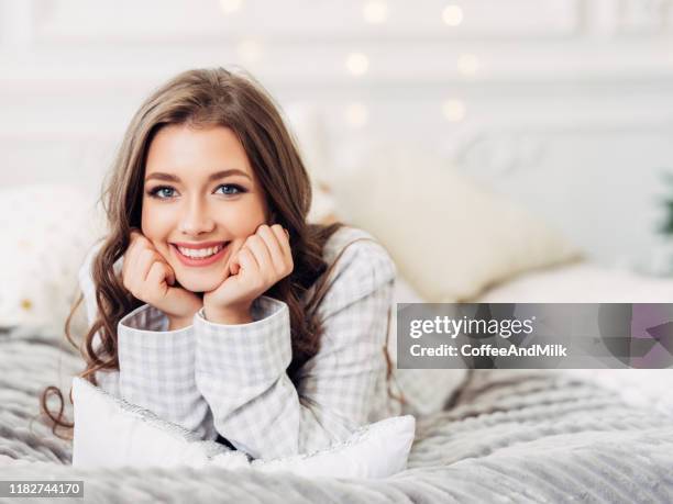 beautiful girl sitting in a cozy atmosphere near the christmas tree - pyjamas stock pictures, royalty-free photos & images