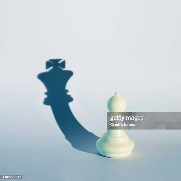 white chess pawn with the shadow of a king - chess concept stock pictures, royalty-free photos & images