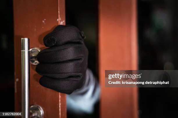 dangerous masked burglar with crowbar breaking into a victim's home door,home insurance concept - einbruch stock-fotos und bilder