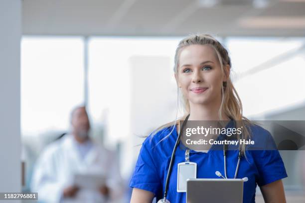 omvårdnad student eller medicinsk praktikant leenden medan promenader genom sjukhuset - female nurse bildbanksfoton och bilder