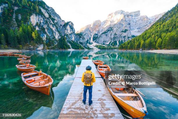 one man standing on a pier at lake braies, south tyrol, italy - greatest stock pictures, royalty-free photos & images