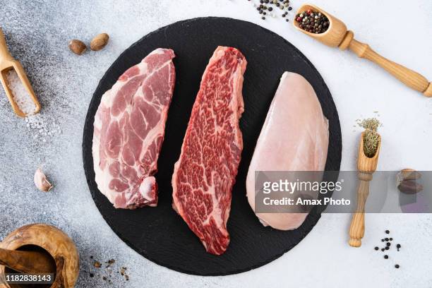 frisches rohes rindfleisch, schweinefleisch und hühnerbrust mit pfefferkörnern, gewürzen und gewürzen, bereit zum grillen. ansicht von oben - beef steak stock-fotos und bilder
