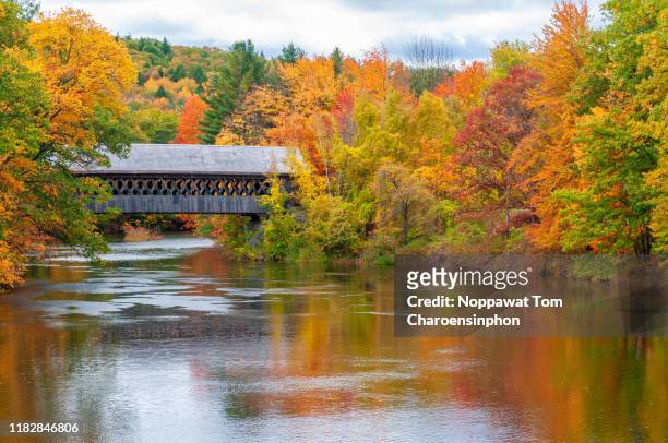 covered bridge with peak autumn color along contoocook river, new hampshire, usa - new hampshire stock-fotos und bilder