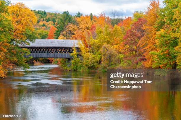 covered bridge with peak autumn color along contoocook river, new hampshire, usa - autumn covered bridge stock pictures, royalty-free photos & images