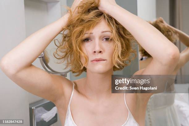 woman in bathroom tearing her hair out - messy hair stock-fotos und bilder