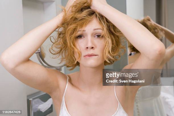 woman in bathroom tearing her hair out - female biting lips stockfoto's en -beelden
