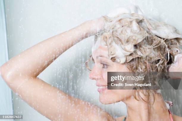 woman washing her hair in the shower - femme shampoing photos et images de collection