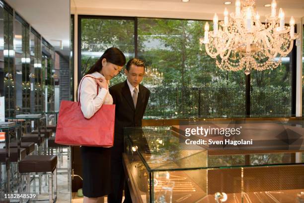 two people looking at jewelry in display cabinets - upper class stock pictures, royalty-free photos & images