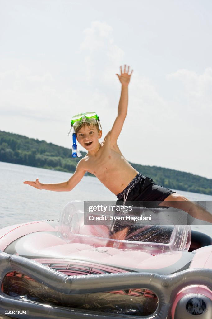Boy Inflatable Raft A Young Boy Standing In An Inflatable Raft On A Lake High-Res Stock ...