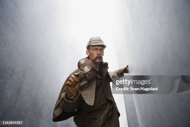 a man dressed like sherlock holmes holding a magnifying glass - investigatore foto e immagini stock
