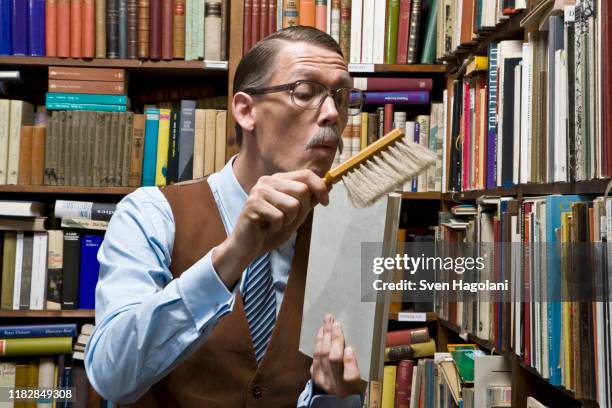 a man using a dust brush on a book - staubwedel stock-fotos und bilder