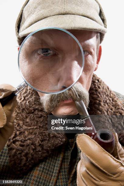 a man dressed up as sherlock holmes with a magnifying glass distorting his eye - deerstalker hat imagens e fotografias de stock