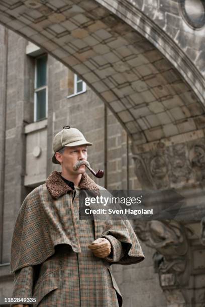 a man dressed up as sherlock holmes standing under a building arch looking away - sherlock holmes 2009 film stock-fotos und bilder