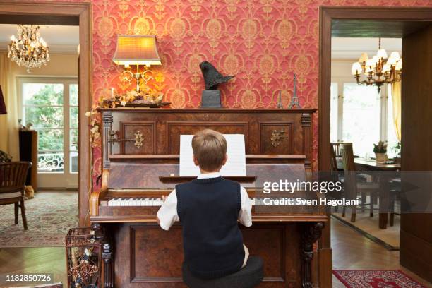 a boy practicing on an old-fashioned upright piano - pianist vintage stock pictures, royalty-free photos & images