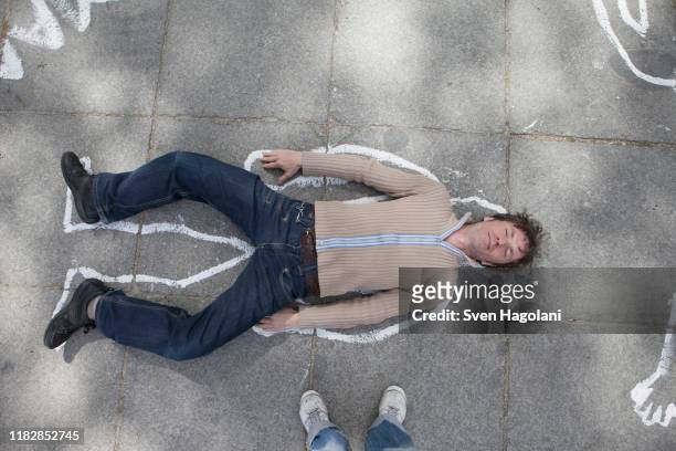high angle view of chalk outline around man lying on street - silhouette à la craie photos et images de collection