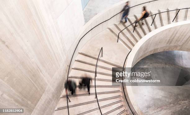 verschwommene bewegung von menschen auf spiraltreppe - architektur stock-fotos und bilder