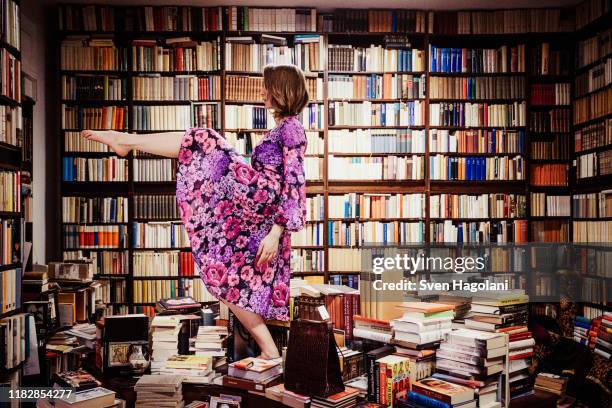 exuberant woman dancing on book stacks in library - fun experience stock pictures, royalty-free photos & images