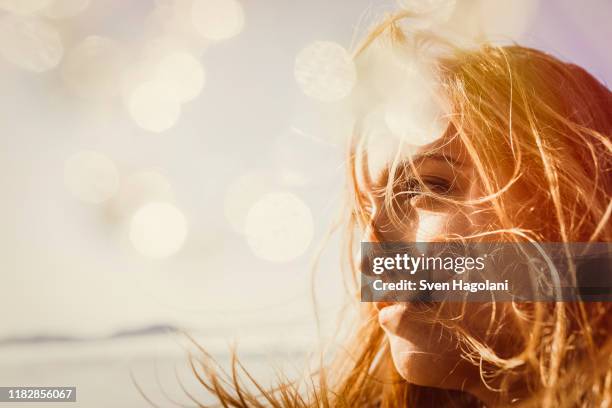 serene woman enjoying sunshine - flatterndes haar stock-fotos und bilder