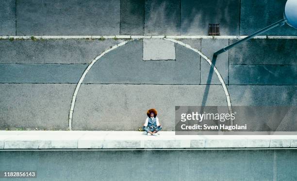 view from above young man meditating on urban sidewalk - lotuspositie stockfoto's en -beelden