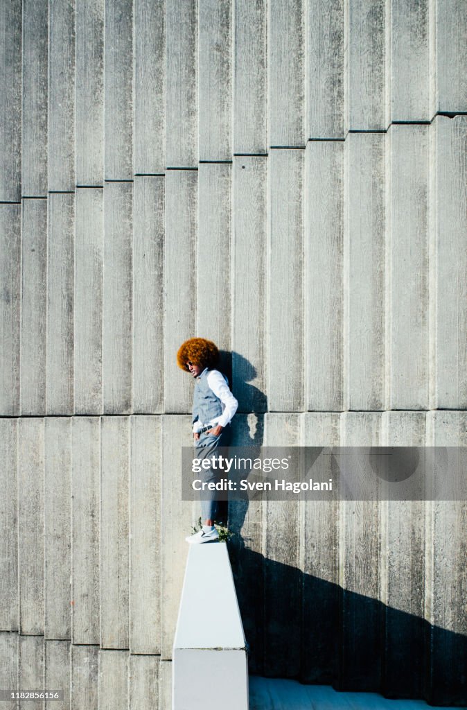 View from above young man with afro laying on sunny urban steps