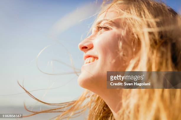 close up carefree, smiling woman enjoying sunshine - sonnenlicht stock-fotos und bilder