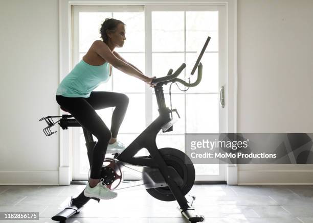 senior woman on exercise bike - heimtrainer stock-fotos und bilder