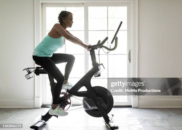 senior woman on exercise bike - spinning bikes stock pictures, royalty-free photos & images