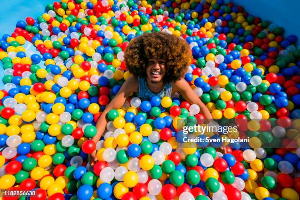 portrait exuberant young man playing in multicolor ball pool - young at heart stock-fotos und bilder