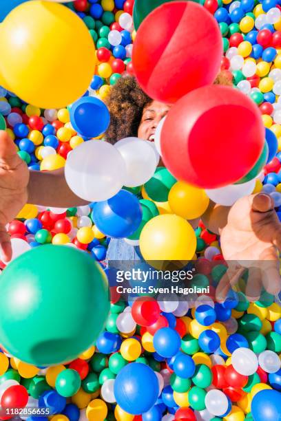happy young man playing in vibrant ball pool - adult ball pit stock pictures, royalty-free photos & images