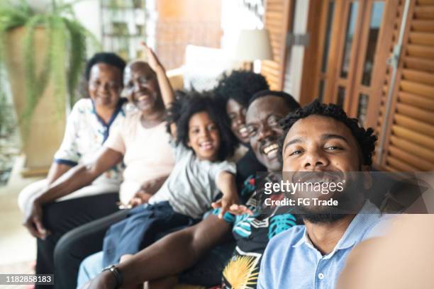 junger mann macht ein selfie seiner familie - familientreffen stock-fotos und bilder