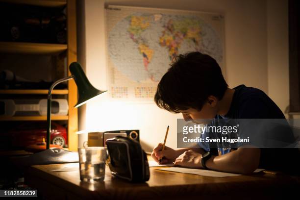 teenage boy studying at table in house - angle poise lamp foto e immagini stock