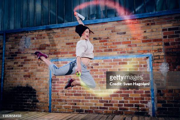 female modern dancer performing with spray paint cans - berlin graffiti stock-fotos und bilder